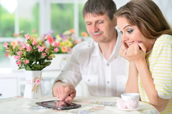 一对年轻夫妇坐在桌旁 看着数码平板电脑 — 图库照片