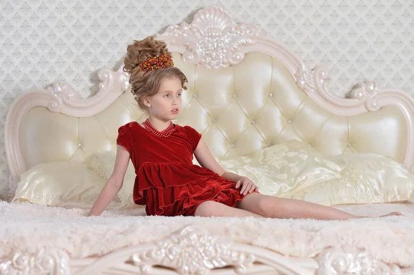 穿着红衣服的可爱小女孩躺在床上 — 图库照片