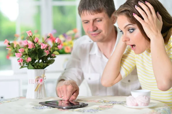 Verrast Jong Paar Zitten Aan Tafel Kijken Naar Digitale Tablet — Stockfoto