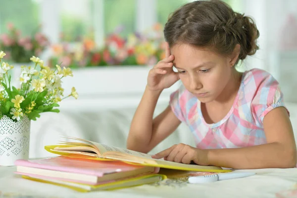 一个可爱的小女孩在家里的桌子边看书 — 图库照片