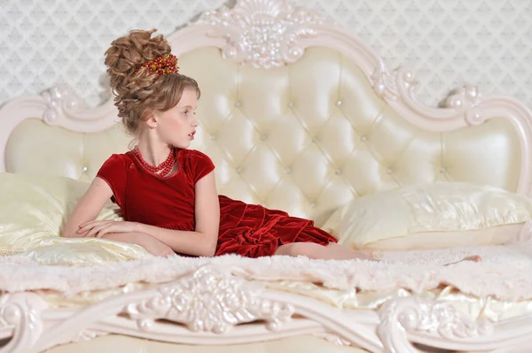 穿着红衣服的可爱小女孩躺在床上 — 图库照片