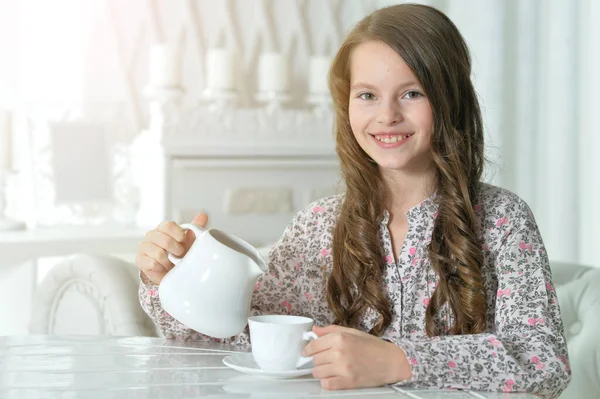 可愛いです女の子飲むお茶にライトキッチン — ストック写真
