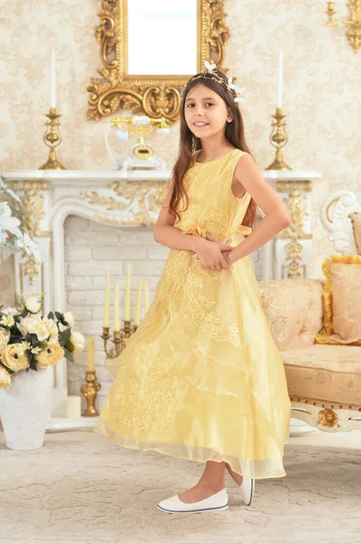 穿着黄色衣服的漂亮姑娘站在壁炉边摆姿势 — 图库照片