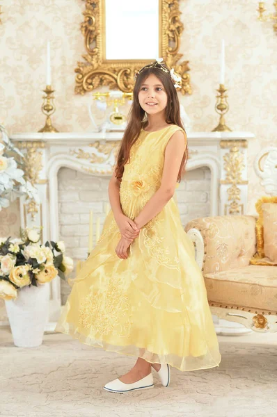 穿着黄色衣服的漂亮姑娘站在壁炉边摆姿势 — 图库照片