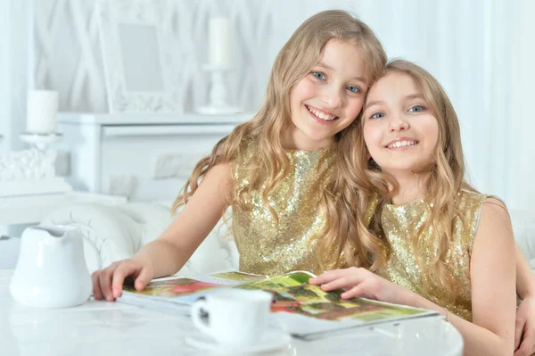 현대 잡지를 가지고 있는 귀여운 쌍둥이 자매 — 스톡 사진