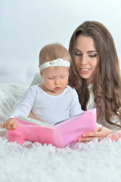 Feliz Joven Madre Con Pequeña Hija Leyendo Libro Mientras Está —  Fotos de Stock