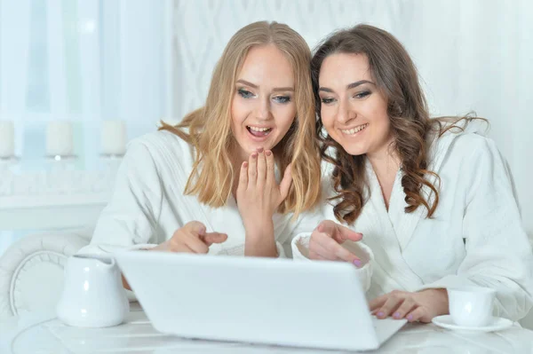 Mulheres jovens em roupões de banho com laptop — Fotografia de Stock