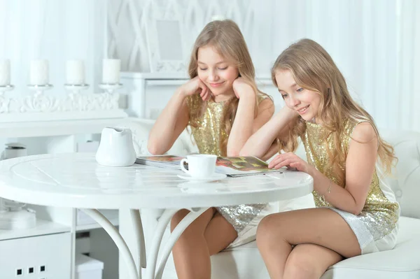 Söta tvillingsystrar med modern tidning — Stockfoto