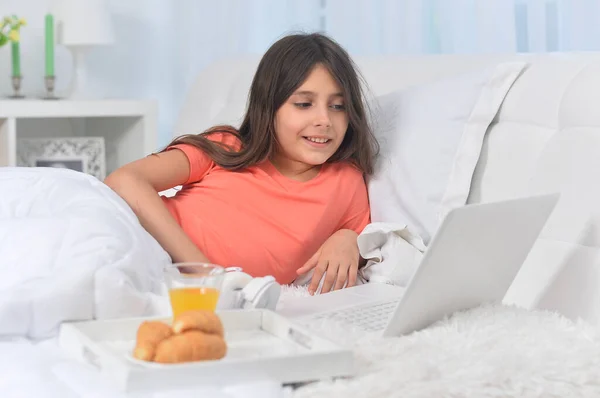 Piękna Dziewczyna Leżąca Miękkim Beżowym Łóżku Laptopem Jedząca Śniadanie — Zdjęcie stockowe