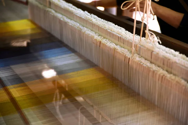 Geleneksel ahşap dokuma tezgahında ipek ören kadınların ellerini yakından izle..