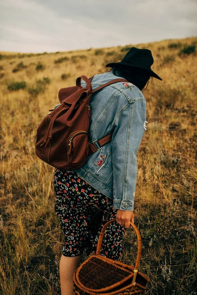 Happy girl walking on field at sunset