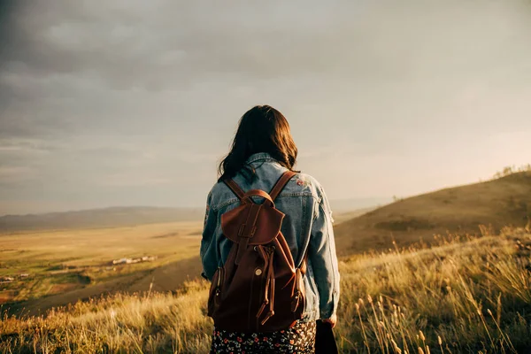 Happy girl walking on field at sunset