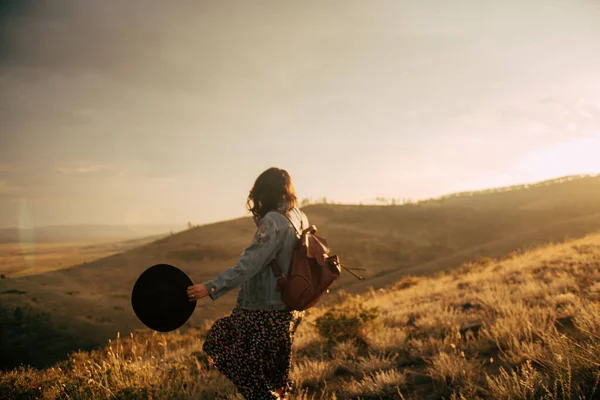 Happy girl walking on field at sunset