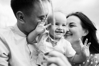 Ebeveynler oğluyla yaz günü çayırda oynarken eğleniyorlar.