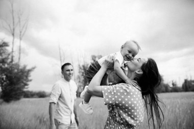 Ebeveynler oğluyla yaz günü çayırda oynarken eğleniyorlar.