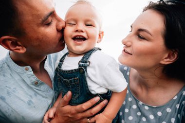 Ebeveynler oğluyla yaz günü çayırda oynarken eğleniyorlar.