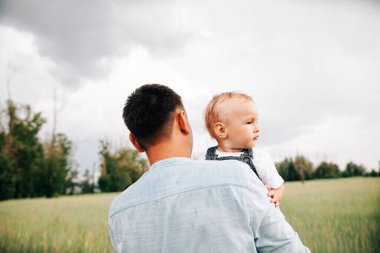 Baba ve oğul yaz günü çayırda birlikte oynuyorlar. 