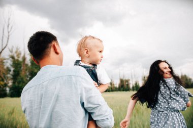 Ebeveynler oğluyla yaz günü çayırda oynarken eğleniyorlar.