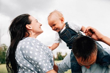 Ebeveynler oğluyla yaz günü çayırda oynarken eğleniyorlar.