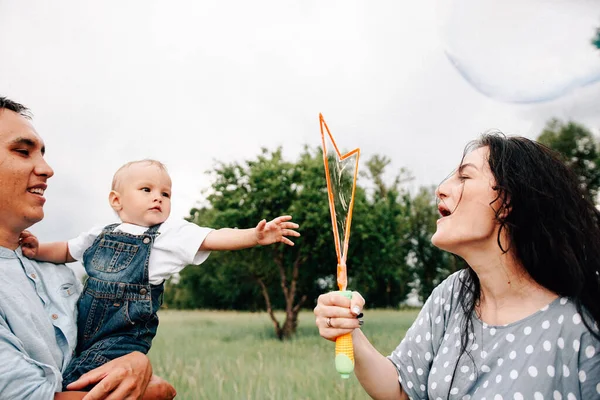 Счастливые Молодые Родители Сын Веселятся Играя Мыльными Пузырями Подгузниках Летний — стоковое фото