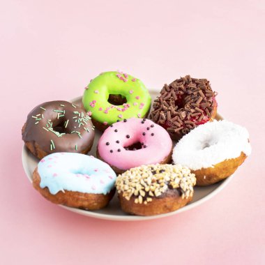 Çörek sır çeşitli ile kaplı ve tatlılar bir plaka üzerinde pembe bir arka plan üzerinde serpilir