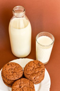 Süt açık cam şişe ve cam cam bardak ve çerezleri beyaz plaka üzerinde 