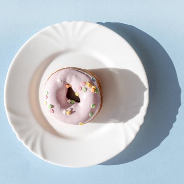 Doğal güneş ışığı altında mavi zemin üzerine beyaz plaka üzerinde buzlanma mor çörek kaplı