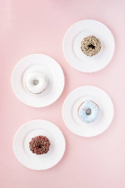 Sır pembe bir arka plan üzerinde dört beyaz tabaklar farklı çörek ile kaplı