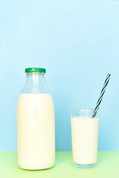 Milch in einer transparenten Glasflasche und in einem Glasbecher mit einem Schlauch auf — Stockfoto