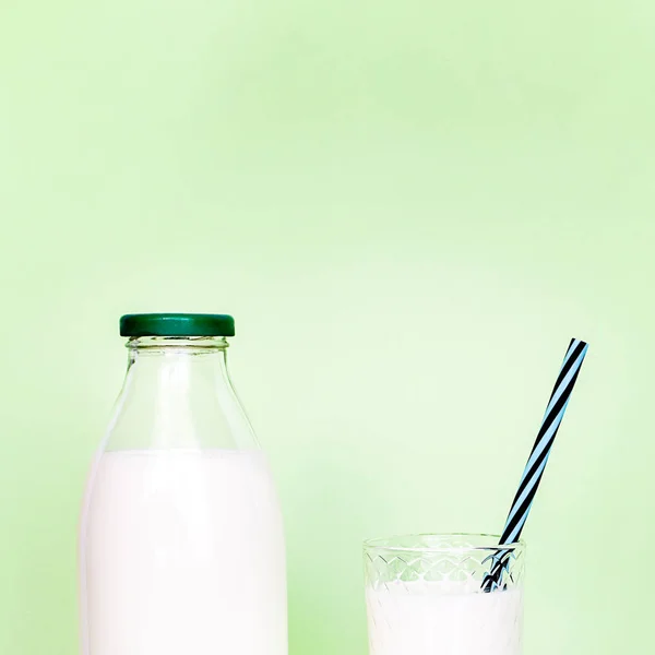 Milk in a glass bottle and a transparent glass with straw