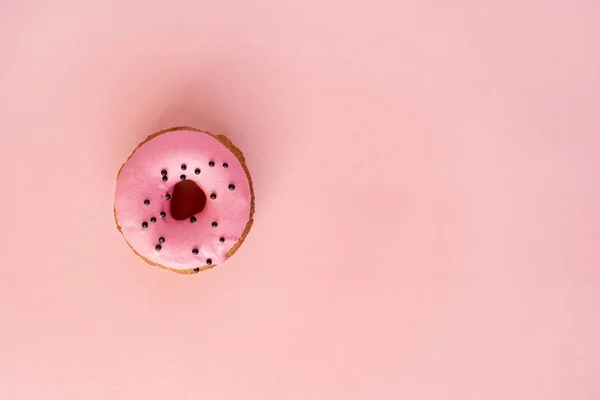 Donut cubierto con glaseado rosa y espolvoreado con redondeles negros — Foto de Stock