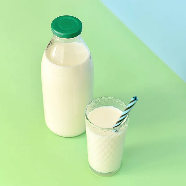 Leche en una botella de vidrio y un vaso transparente con paja — Foto de Stock