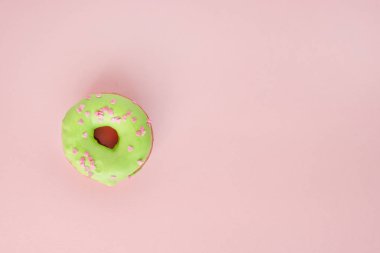 Çörek yeşil sır ile kaplı ve pembe bir arka plan üzerinde pembe kalpler serpilir