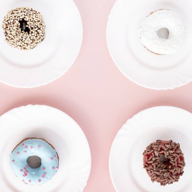 Sır pembe bir arka plan üzerinde dört beyaz tabaklar farklı çörek ile kaplı