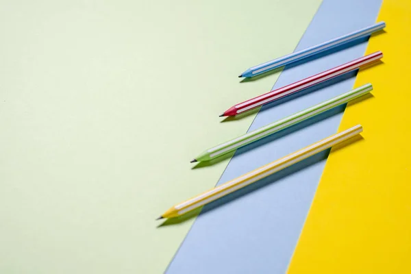 Multi-coloridas listradas belos lápis em fundo tri-color — Fotografia de Stock