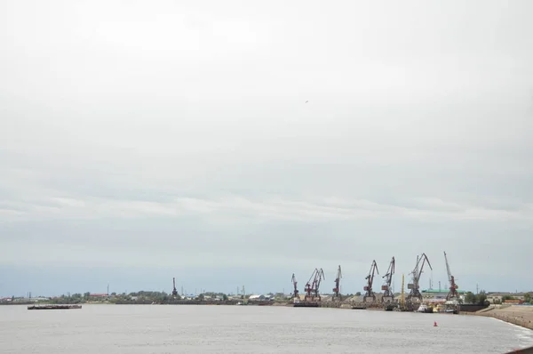 Un puerto fluvial con grúas y una barcaza que flota —  Fotos de Stock