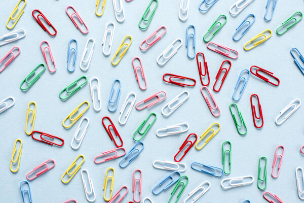 Multi-colored paper clips on blue background