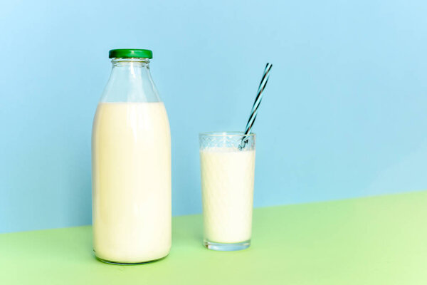 Молоко в стеклянной бутылке и прозрачное стекло с соломой
 