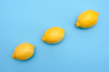 Mavi bir yüzey üzerinde üst üste üç sarı limon