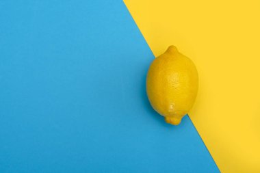 Sarı-mavi arka plan üzerinde bir sarı limon. Üstten görünüm.