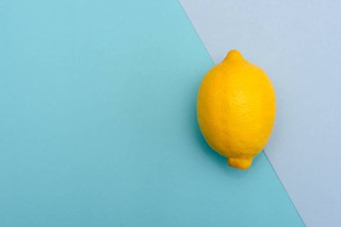 Farklı tonları mavi bir arka plan üzerinde bir sarı limon. Üstten görünüm.