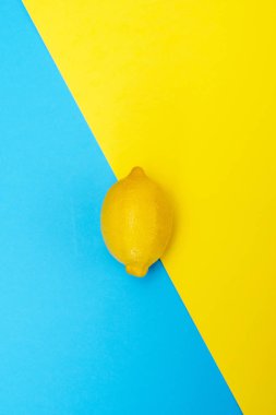 Sarı-mavi arka plan üzerinde bir sarı limon. Üstten görünüm.