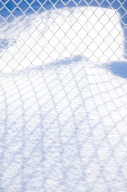Kar güneşli bir günde büyük bir metal ızgara gölgesi düşüyor