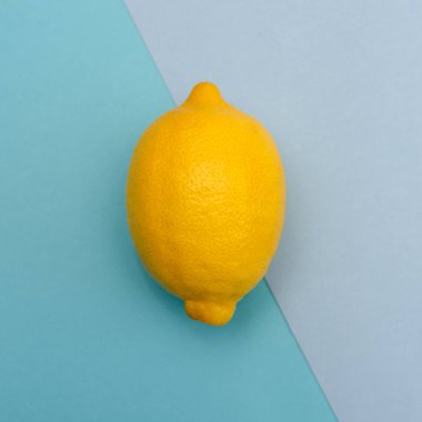 Farklı tonları mavi bir arka plan üzerinde bir sarı limon. Üstten görünüm.