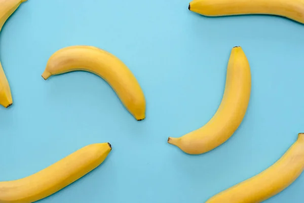 Bakgrunden mogna bananer spridda slumpmässigt på blå yta — Stockfoto