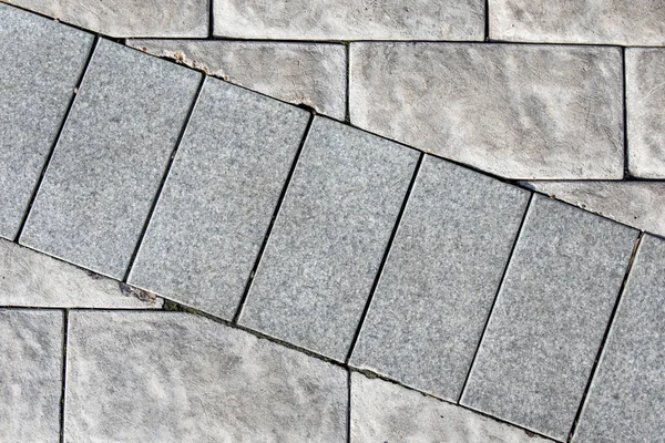 El fondo de una pared de ladrillo de piedra de color gris, donde un número de ladrillos de una sombra diferente pasa a través de — Foto de Stock