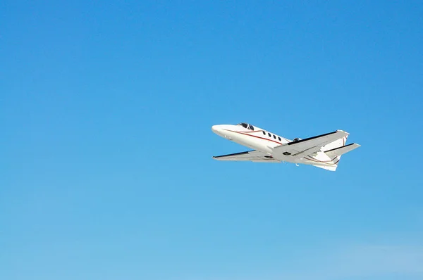 Um avião privado branco voa no céu azul — Fotografia de Stock