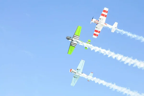 Tres planos de colores verde y blanco vuelan dejando un rastro en el cielo azul . — Foto de Stock