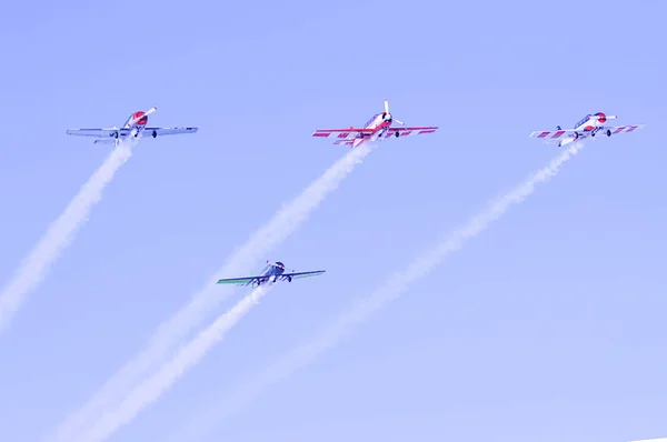 Quatro pequenas aeronaves voando deixando um rastro branco — Fotografia de Stock