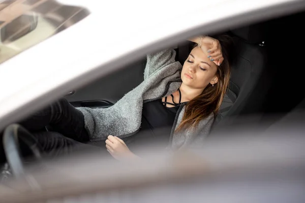 Молодая девушка в черной одежде сидит в машине на пассажирском сидении — стоковое фото